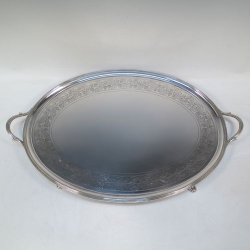 A very elegant Antique Georgian Sterling Silver tray, having an oval body with a plain central ground surrounded by a band of hand-engraved acorn and oak leaf decoration, with an applied reeded border, and two cast reeded handles, all sitting on four cast flange feet. This beautiful antique silver tray was made by Peter, Anne, and William Bateman of London in 1802. The dimensions of this fine hand-made antique silver tray are length (inc. handles) 55 cms (21.75 inches), width 35.5 cms (14 inches), height 4.5 cms (1.75 inches), and it weighs approx. 1,795g (58 troy ounces).   