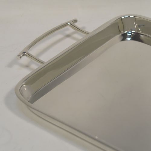 A very handsome and stylish Art Deco Sterling silver tray, having a very plain ground, a raised gallery border with rounded corners, two side-handles, and sitting on a flat base. This elegant Art Deco silver tray was made by Walker and Hall of Sheffield in 1932. The dimensions of this fine hand-made silver tray are length (inc. handles) 38 cms (15 inches), width 18.5 cms (7.25 inches), and it weighs approx. 620g (20 troy ounces).   