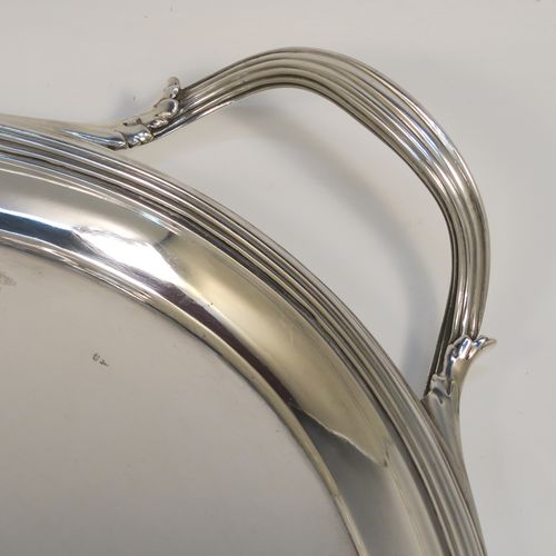 A very elegant Antique Georgian Sterling Silver oval two-handled tea tray, having a plain ground with a hand-engraved full armorial crest, an applied Reeded border, two cast reeded side handles, and all sitting on a flat base. This very handsome antique silver tray was made by Elizabeth Jones of London in 1794. The dimensions of this fine hand-made antique silver tray are length (inc. handles) 56 cms (22 inches), width 36 cms (14.25 inches), and it weighs approx. 1,923g (62 troy ounces).   