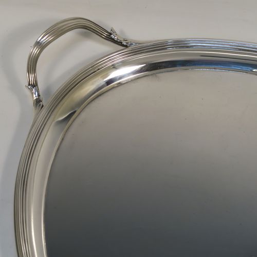 A very elegant Antique Georgian Sterling Silver oval two-handled tea tray, having a plain ground with a hand-engraved full armorial crest, an applied Reeded border, two cast reeded side handles, and all sitting on a flat base. This very handsome antique silver tray was made by Elizabeth Jones of London in 1794. The dimensions of this fine hand-made antique silver tray are length (inc. handles) 56 cms (22 inches), width 36 cms (14.25 inches), and it weighs approx. 1,923g (62 troy ounces).   