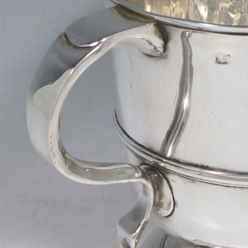 Antique Georgian George II Sterling silver trophy loving cup, having a plain round body with central reeded band, two scroll side-handles which are part-marked with a makers mark, and sitting on a pedestal foot. Made by Benjamin Blakely of London in 1738. The dimensions of this fine silver loving cup are height 14.5 cms (5.75 inches), spread across handles 23 cms (9 inches), and it weighs approx. 511g (16.5 troy ounces).