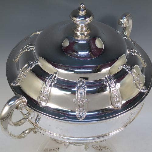 A very impressive and large Antique Edwardian  Sterling Silver trophy cup and cover, having a round body with applied floral strap-work decoration, two flying scroll side-handles, a central applied girdle band, a pull-off lid with matching applied strap-work and a cast round finial, and all sitting on a stepped pedestal foot, again, with matching decoration. Made by Alexander Clark of Sheffield in 1906. The dimensions of this fine hand-made antique silver trophy cup and cover are height 48 cms (19 inches), spread across arms 37 cms (14.5 inches), and it weighs approx. 2,842g (92 troy ounces). Please note that this item has a full armorial crest engraved on one side. 