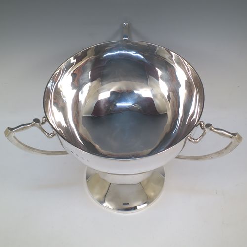 A very large and heavy Antique Edwardian Sterling Silver Art Nouveau three-handled trophy cup, having a plain round body, with three side-handles, and sitting on a plain pedestal foot. Made by Alexander Clarke & Co., of Birmingham in 1907. The dimensions of this fine hand-made large antique silver trophy cup are height 31 cms (12.25 inches), diameter of main body 27 cms (10.5 inches), and it weighs approx. 2,485g (80 troy ounces).  