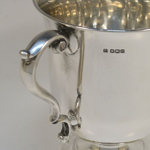 A very handsome Antique Sterling Silver trophy cup in a George III style, having a plain round bellied body, two scroll side-handles, and all sitting on a round pedestal foot. This elegant antique sterling silver trophy cup was made by Martin Hall and Co. Ltd., of Sheffield in 1922. The dimensions of this fine hand-made silver trophy cup are height 16 cms (6.3 inches), spread across arms 21.5 cms (8.5 inches), and it weighs approx. 390g (12.6 troy ounces).   