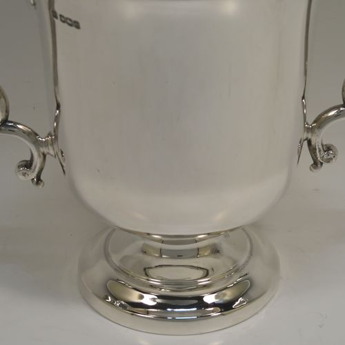 A very handsome Antique Sterling Silver trophy cup in a George III style, having a plain round bellied body, two scroll side-handles, and all sitting on a round pedestal foot. This elegant antique sterling silver trophy cup was made by Martin Hall and Co. Ltd., of Sheffield in 1922. The dimensions of this fine hand-made silver trophy cup are height 16 cms (6.3 inches), spread across arms 21.5 cms (8.5 inches), and it weighs approx. 390g (12.6 troy ounces).   