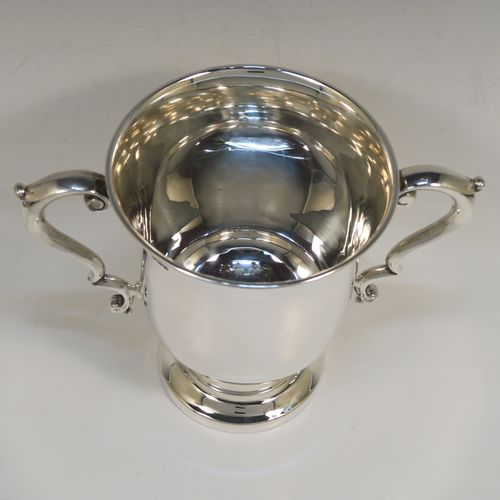 A very handsome Antique Sterling Silver trophy cup in a George III style, having a plain round bellied body, two scroll side-handles, and all sitting on a round pedestal foot. This elegant antique sterling silver trophy cup was made by Martin Hall and Co. Ltd., of Sheffield in 1922. The dimensions of this fine hand-made silver trophy cup are height 16 cms (6.3 inches), spread across arms 21.5 cms (8.5 inches), and it weighs approx. 390g (12.6 troy ounces).   