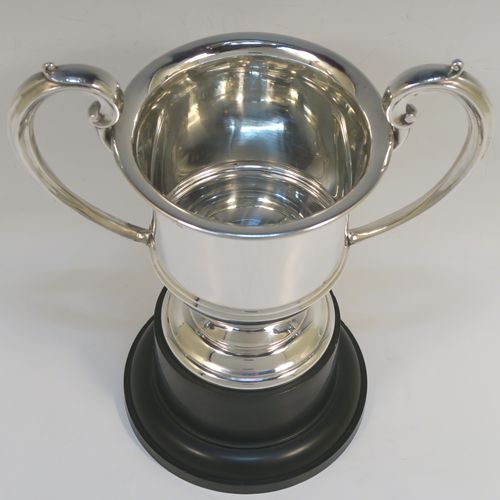 An elegant Sterling Silver trophy loving cup and plinth, having a plain round body with a central reeded band, two scroll side-handles, and sitting on a round pedestal foot, and original black Bakelite plinth. This handsome silver loving cup trophy was made by A. E. Poston & Co., of Birmingham in 1936. The dimensions of this fine silver loving trophy cup are (without plinth) height 16.5 cms (6.5 inches), spread across handles 20 cms (8 inches), and it weighs approx. 240g (7.7 troy ounces).  