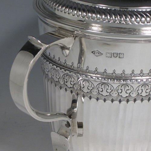 Antique Sterling silver trophy cup and cover, in a George II style, having a round body with hand-chased fluted and floral decoration, two scroll side-handles, a pull-off lid with cast finial, and sitting on a pedestal foot. Made Johnson, Walker & Tolehurst of London in 1912. The dimensions of this fine hand-made silver trophy cup and cover are height 24 cms (9.5 inches), spread across arms 26.5 cms (10.5 inches), and it weighs approx. 1,056g (34 troy ounces).   