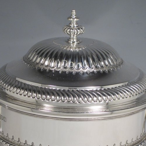 Antique Sterling silver trophy cup and cover, in a George II style, having a round body with hand-chased fluted and floral decoration, two scroll side-handles, a pull-off lid with cast finial, and sitting on a pedestal foot. Made Johnson, Walker & Tolehurst of London in 1912. The dimensions of this fine hand-made silver trophy cup and cover are height 24 cms (9.5 inches), spread across arms 26.5 cms (10.5 inches), and it weighs approx. 1,056g (34 troy ounces).   