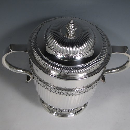 Antique Sterling silver trophy cup and cover, in a George II style, having a round body with hand-chased fluted and floral decoration, two scroll side-handles, a pull-off lid with cast finial, and sitting on a pedestal foot. Made Johnson, Walker & Tolehurst of London in 1912. The dimensions of this fine hand-made silver trophy cup and cover are height 24 cms (9.5 inches), spread across arms 26.5 cms (10.5 inches), and it weighs approx. 1,056g (34 troy ounces).   