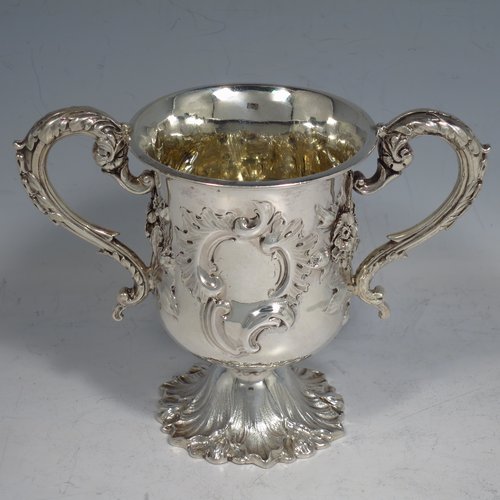 An Antique Victorian Sterling silver miniature trophy cup, in a Campana style, having a baluster body with a vacant cartouche on one side, and hand-chased floral decoration, with two cast floral scroll handles, a gold-gilt interior, and sitting on a spreading Acanthus leaf pedestal foot. Made by Charles Fox of London in 1839. The dimensions of this fine antique silver trophy cup are height 11 cms (4.25 inches), spread across handles 14 cms (5.5 inches), and it weighs approx. 185g (6 troy ounces).    