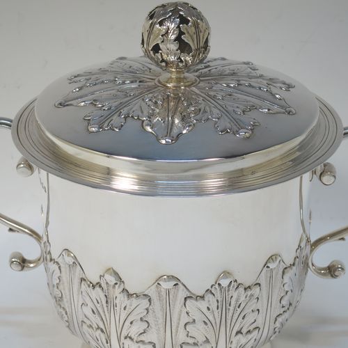 A very handsome Sterling Silver trophy cup and cover, in the shape of a lidded Porringer, having a round body with hand-chased Anthemion leaf decoration, with two scroll side-handles, a lift-off cover with matching decoration and a pierced floral finial, and all sitting on a stepped pedestal foot. Made by Charles Stuart Harris of London in 1925. The dimensions of this fine hand-made antique silver trophy porringer cup are height 18 cms (7 inches), spread across handles 21 cms (8.25 inches), and it weighs approx. 748g (24 troy ounces).   