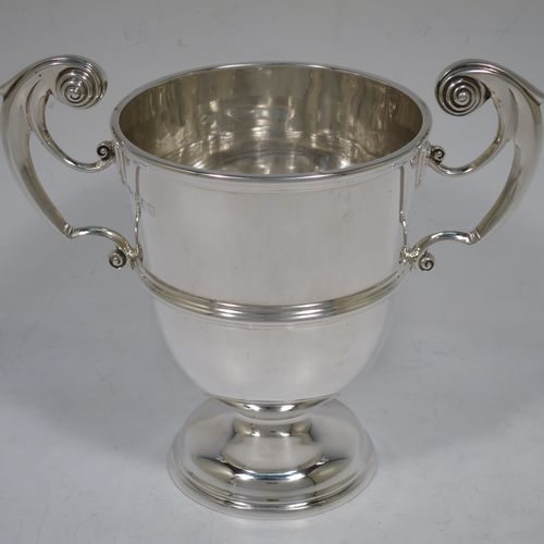 A very handsome Antique Edwardian Sterling Silver pair of trophy cups in a George II style, having plain round bodies with applied reeded borders, two flying scroll side-handles, central applied girdle bands, and all sitting on stepped pedestal feet. Made by Skinner and Co., of Sheffield in 1908. The dimensions of these fine hand-made antique silver trophy cups are height 14.5 cms (5.75 inches), spread across arms 17 cms (7.75 inches), and they weigh a total of approx. 624g (20 troy ounces).   