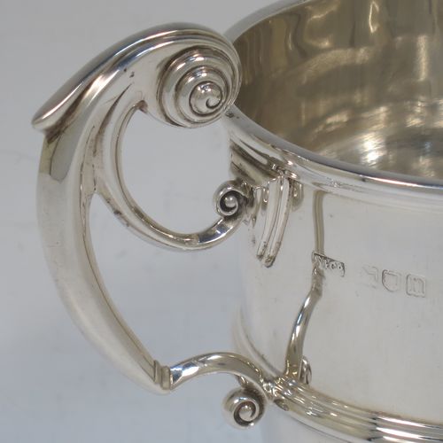 A very handsome Antique Edwardian Sterling Silver trophy cup in a George II style, having a plain round body with applied reeded borders, two flying scroll side-handles, a central applied girdle band, and all sitting on a stepped pedestal foot. Made by Skinner and Co., of Sheffield in 1908. The dimensions of this fine hand-made antique silver trophy cup are height 14.5 cms (5.75 inches), spread across arms 17 cms (7.75 inches), and it weighs approx. 312g (10 troy ounces).  