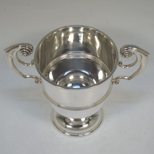 A very handsome Antique Edwardian Sterling Silver trophy cup in a George II style, having a plain round body with applied reeded borders, two flying scroll side-handles, a central applied girdle band, and all sitting on a stepped pedestal foot. Made by Skinner and Co., of Sheffield in 1908. The dimensions of this fine hand-made antique silver trophy cup are height 14.5 cms (5.75 inches), spread across arms 17 cms (7.75 inches), and it weighs approx. 312g (10 troy ounces).  