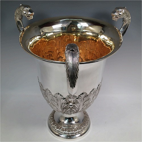 A very large, heavy, and handsome Antique Edwardian Sterling Silver three-handled trophy cup, having a round body with tapering sides and hand-chased half anthemion leaf decoration, with a  gold-gilt interior, three cast flying scroll handles with leopard face terminals, and all sitting on a pedestal foot. Made by Goldsmiths and Silversmiths of London in 1905. The dimensions of this fine hand-made large antique silver trophy cup are height 43 cms (17 inches), spread across arms 38 cms (15 inches), and it weighs approx. 3,225g (104 troy ounces).    