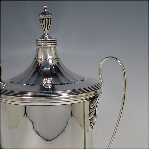 A very handsome Sterling Silver trophy cup and cover in a George III neoclassical style, having a round body with tapering sides and half-fluted decoration, with hand-chased reeded borders, two looped side-handles, an original cover with matching decoration and cast urn finial, and all sitting on a pedestal foot. Made by Robert Pringle  of London in 1923. The dimensions of this fine hand-made silver trophy cup and cover are height 33 cms (13 inches), spread across arms 21 cms (8.25 inches), and it weighs approx. 879g (28 troy ounces).    