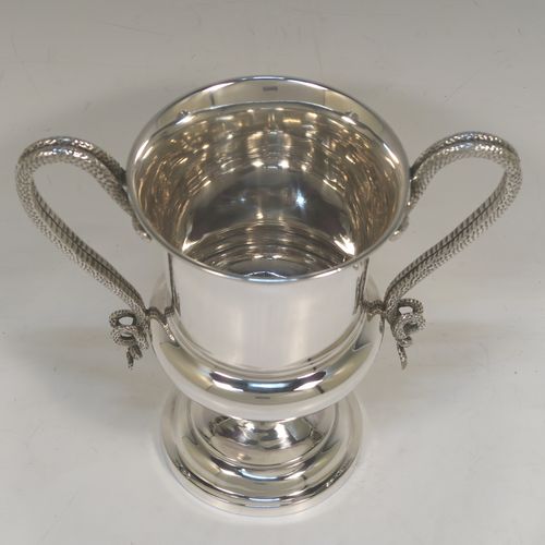 A very handsome Antique Edwardian Sterling Silver trophy cup, having a plain round bellied body with tapering sides, two looped side-handles in the form of twin snakes, and all sitting on a stepped pedestal foot. This elegant silver trophy cup was made by Charles Stuart Harris of London in 1906. The dimensions of this fine hand-made antique silver trophy cup are height 17.5 cms (7 inches), spread across arms 18.5 cms (7.25 inches), and it weighs approx. 438g (14 troy ounces).  