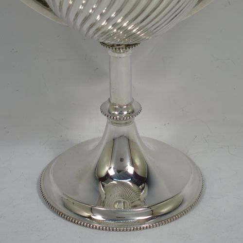 A handsome Antique Edwardian Sterling Silver trophy cup in a George III neoclassical style, having a round body with tapering sides and half-fluted decoration, two plain flat-topped side-handles, and all sitting on a pedestal foot with bead-edged borders. Made by Mappin and Webb of London in 1904. The dimensions of this fine hand-made antique silver trophy cup are height 23 cms (9 inches), spread across arms 18 cms (7 inches), and it weighs approx. 558g (18 troy ounces).    