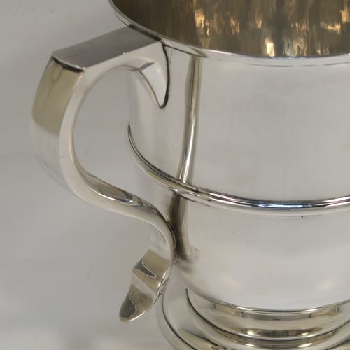 A very elegant Antique Edwardian Sterling Silver trophy loving cup, having a plain round body with a  central reeded band, two flat-topped scroll side-handles, and sitting on a round pedestal foot. This handsome antique silver loving cup trophy was made by Robert Dicker of London in 1904. The dimensions of this fine antique silver loving cup are height 14.5 cms (5.75 inches), spread across handles 21.5 cms (8.5 inches), and it weighs approx. 604g (19.5 troy ounces).   