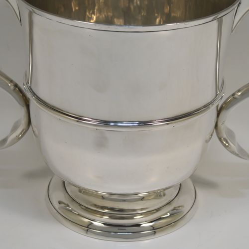 A very elegant Antique Edwardian Sterling Silver trophy loving cup, having a plain round body with a  central reeded band, two flat-topped scroll side-handles, and sitting on a round pedestal foot. This handsome antique silver loving cup trophy was made by Robert Dicker of London in 1904. The dimensions of this fine antique silver loving cup are height 14.5 cms (5.75 inches), spread across handles 21.5 cms (8.5 inches), and it weighs approx. 604g (19.5 troy ounces).   