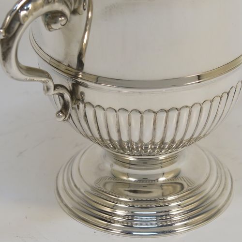 A fantastic quality Sterling Silver trophy cup and cover, having a round body with hand-chased half-fluted, with two cast scroll side-handles, a lift-off cover with matching decoration and a cast urn-shaped finial, and all sitting on a stepped pedestal foot. This very handsome silver trophy cup and cover was made by Henry Phillips of London in 193.5 The dimensions of this fine hand-made silver trophy cup are height 15 cms (6 inches), spread across handles 14.5 cms (5.75 inches), and it weighs approx. 375g (12 troy ounces).  