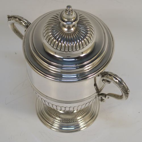 A fantastic quality Sterling Silver trophy cup and cover, having a round body with hand-chased half-fluted, with two cast scroll side-handles, a lift-off cover with matching decoration and a cast urn-shaped finial, and all sitting on a stepped pedestal foot. This very handsome silver trophy cup and cover was made by Henry Phillips of London in 193.5 The dimensions of this fine hand-made silver trophy cup are height 15 cms (6 inches), spread across handles 14.5 cms (5.75 inches), and it weighs approx. 375g (12 troy ounces).  