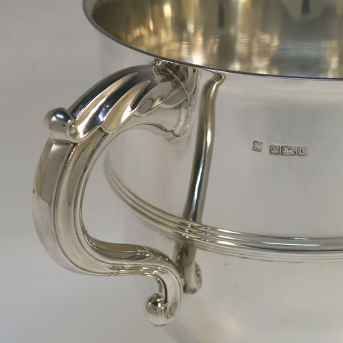 A very handsome Sterling Silver trophy cup in a George III neoclassical style, having a round plain body with tapering sides, an applied central reeded band, two cast scroll side-handles, and all sitting on a stepped pedestal foot. This elegant silver trophy cup was made by Fordham and Faulkner of Sheffield in 1925. The dimensions of this fine hand-made silver trophy cup are height 18 cms (7 inches), spread across arms 27 cms (10.5 inches), and it weighs approx. 620g (20 troy ounces).   