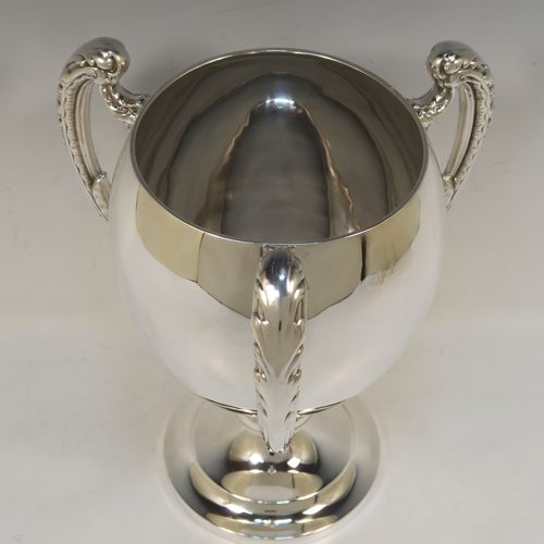 A handsome Sterling Silver trophy loving cup, having a plain round bellied body, three cast scroll side-handles with anthemion leaf decoration, and sitting on a plain round pedestal foot. This elegant silver three-handled loving cup trophy was made by Elkington & Co., of Birmingham in 1932. The dimensions of this fine hand-made silver trophy loving cup are height 26 cms (10.25 inches), width across handles 21.5 cms (8.5 inches), and it weighs approx. 852g (27.5 troy ounces).   