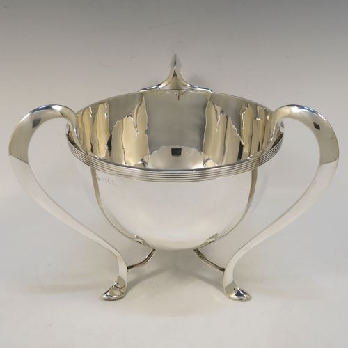 An elegant and heavy Antique Edwardian Sterling Silver three-handled Loving cup bowl, having a plain round body with tapering sides, with three scroll  side-handled feet. This handsome antique silver loving cup trophy bowl was made by Horace Woodward of London in 1903. The dimensions of this fine hand-made sterling silver trophy cup bowl are height 21 cms (8.25 inches), diameter of main body 20 cms (8 inches), and it weighs approx. 1,198g (38.6 troy ounces).  