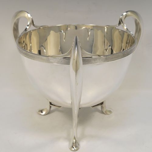 An elegant and heavy Antique Edwardian Sterling Silver three-handled Loving cup bowl, having a plain round body with tapering sides, with three scroll  side-handled feet. This handsome antique silver loving cup trophy bowl was made by Horace Woodward of London in 1903. The dimensions of this fine hand-made sterling silver trophy cup bowl are height 21 cms (8.25 inches), diameter of main body 20 cms (8 inches), and it weighs approx. 1,198g (38.6 troy ounces).  