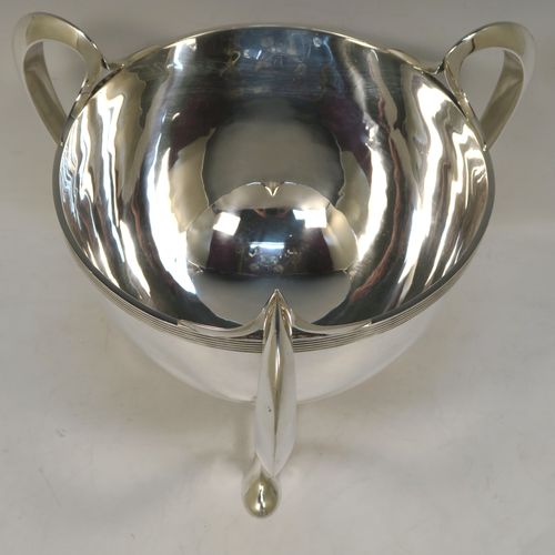 An elegant and heavy Antique Edwardian Sterling Silver three-handled Loving cup bowl, having a plain round body with tapering sides, with three scroll  side-handled feet. This handsome antique silver loving cup trophy bowl was made by Horace Woodward of London in 1903. The dimensions of this fine hand-made sterling silver trophy cup bowl are height 21 cms (8.25 inches), diameter of main body 20 cms (8 inches), and it weighs approx. 1,198g (38.6 troy ounces).  