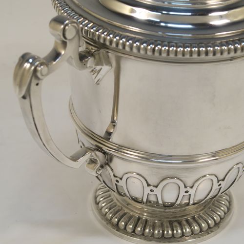 A fantastic quality Antique style Sterling Silver trophy cup and cover, having a mainly plain round body with applied melon fluting and gadroon borders, with two cast scroll side-handles, a lift-off cover with matching decoration and a cast urn-shaped finial, and all sitting on a pedestal foot. This very handsome antique silver trophy cup and cover was made by Mappin and Webb of London in 1931. The dimensions of this fine hand-made antique silver trophy cup are height 18.5 cms (7.25 inches), spread across handles 21 cms (8.25 inches), and it weighs approx. 788g (25 troy ounces).   