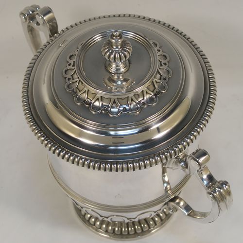 A fantastic quality Antique style Sterling Silver trophy cup and cover, having a mainly plain round body with applied melon fluting and gadroon borders, with two cast scroll side-handles, a lift-off cover with matching decoration and a cast urn-shaped finial, and all sitting on a pedestal foot. This very handsome antique silver trophy cup and cover was made by Mappin and Webb of London in 1931. The dimensions of this fine hand-made antique silver trophy cup are height 18.5 cms (7.25 inches), spread across handles 21 cms (8.25 inches), and it weighs approx. 788g (25 troy ounces).   