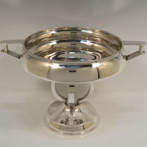 An unusual Art Deco style Sterling Silver two-handled trophy cup bowl, having a plain round body with two side-handles and flat thumb-pieces, all sitting on a round pedestal foot with four convex and square cross-section arms. This beautiful Art Deco silver trophy bowl was made in Birmingham in 1934. The dimensions of this fine hand-made sterling silver trophy cup bowl are height 17 cms (6.75 inches), width across handles 26.5 cms (10.5 inches), and it weighs approx. 589g (19 troy ounces).   