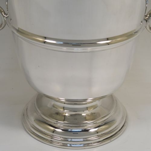 A very handsome Antique Sterling Silver trophy cup in a George II style, having a plain round body with applied reeded borders, two flying scroll side-handles, a central applied girdle band, and all sitting on a stepped pedestal foot. This elegant antique silver trophy cup was made in Birmingham in 1911. The dimensions of this fine hand-made antique silver trophy cup are height 23 cms (9 inches), spread across arms 26 cms (10.25 inches), and it weighs approx. 861g (27.8 troy ounces).   