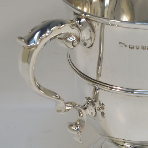 A very elegant and classical Antique Victorian Sterling Silver trophy loving cup, having a plain round body with a central reeded band, two anthemion leaf topped scroll side-handles, and sitting on a round pedestal foot. This handsome antique silver loving cup trophy was made by D. and C. Houle of London in 1875. The dimensions of this fine antique silver loving cup are height 14.5 cms (5.75 inches), spread across handles 21.5 cms (8.5 inches), and it weighs approx. 470g (15 troy ounces).   