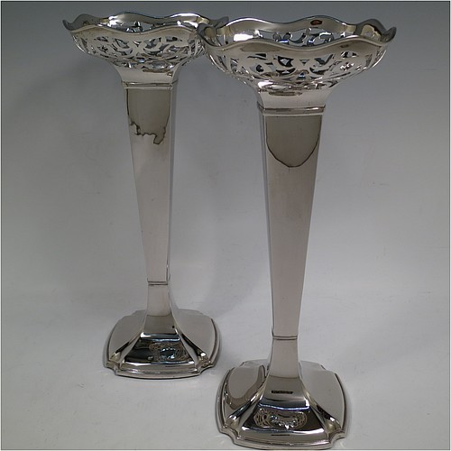 A very handsome and large pair of Antique Sterling Silver table flower vases, having plain square cross-section panelled bodies with tapering sides, with hand-pierced floral and scroll style decoration at the top, and sitting on pedestal feet with cut corners. Made by Charles Cheshire of Chester in 1918. The dimensions of these fine hand-made antique silver pair of vases are height 28 cms (11 inches), and width at top 13 cms (5 inches).    