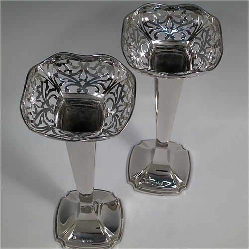 A very handsome and large pair of Antique Sterling Silver table flower vases, having plain square cross-section panelled bodies with tapering sides, with hand-pierced floral and scroll style decoration at the top, and sitting on pedestal feet with cut corners. Made by Charles Cheshire of Chester in 1918. The dimensions of these fine hand-made antique silver pair of vases are height 28 cms (11 inches), and width at top 13 cms (5 inches).    