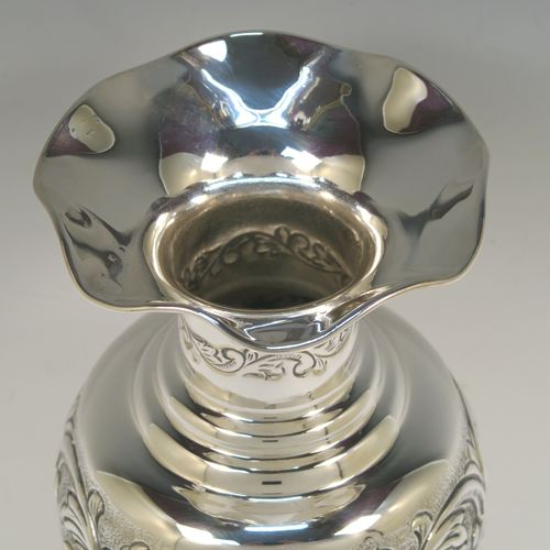 A pretty Scottish Sterling Silver large table flower vase, having a round bellied body, with hand-chased floral decoration, and sitting on a pedestal foot. This beautiful sterling silver single vase was made by the Cooper Brothers of Edinburgh in 2004. The dimensions of this fine hand-made silver vase are height 29 cms (11.5 inches), diameter of main body 12 cms (4.75 inches), and it weighs approx. 498g (16 troy ounces). Please note that this vase is not loaded.   