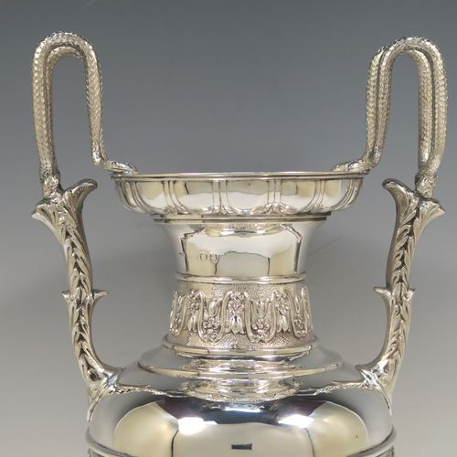 A large and heavy Antique Victorian Sterling Silver Neoclassical style single vase, having an amphora shape with a round body and hand-chased bands of floral, anthemion leaf, and fluted decoration, with two cast side handles, and all sitting on a plain round pedestal foot. This beautiful large antique silver vase was made by William Hutton and Sons of London in 1893. The dimensions of this fine hand-made antique silver vase are height 39 cms (15.3 inches), spread across arms 19 cms (7.5 inches), diameter of body at widest point 15 cms (6 inches), and it weighs approx. 1,117g (36 troy ounces). Please note that this vase is not loaded.   