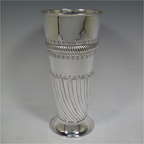 A very handsome Antique Victorian Sterling Silver large table flower vase, having a tapering round body, with hand-chased swirl fluted decoration, an oval vacant cartouche surrounded by hand-chased anthemion leaves and scrolls, with an upper band of gadroon rope-twist work, and sitting on a pedestal foot. Made by Thomas Bradbury of London in 1894. The dimensions of this fine hand-made antique silver vase are height 27.5 cms (10.75 inches), diameter at top 13 cms (5 inches), and it weighs approx. 433g (14 troy ounces). Please note that this vase is not loaded.    