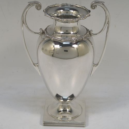 A heavy and very handsome Antique Sterling Silver single vase, having a plain round body with tapering sides, with two flying scroll side handles, with applied shaped gadroon top borders, and all sitting on a pedestal foot with a square base. Made by Stewart Dawson and Co., of Birmingham in 1912. The dimensions of this fine hand-made antique silver vase are height 17 cms (6.5 inches), spread across arms 12 cms (4.75 inches), diameter of body at widest point 8 cms (3 inches), and it weighs approx. 311g (10 troy ounces). Please note that this vase is not loaded.   