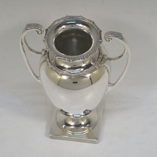 A heavy and very handsome Antique Sterling Silver single vase, having a plain round body with tapering sides, with two flying scroll side handles, with applied shaped gadroon top borders, and all sitting on a pedestal foot with a square base. Made by Stewart Dawson and Co., of Birmingham in 1912. The dimensions of this fine hand-made antique silver vase are height 17 cms (6.5 inches), spread across arms 12 cms (4.75 inches), diameter of body at widest point 8 cms (3 inches), and it weighs approx. 311g (10 troy ounces). Please note that this vase is not loaded.   