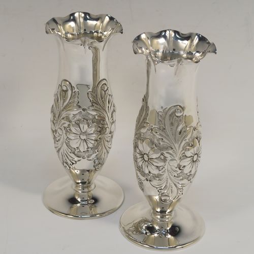 A very pretty Antique Edwardian Sterling Silver pair of table flower vases, having round hand-chased bodies with bellied sides and floral decoration, and all sitting on pedestal feet. These beautiful antique silver vases were made by Charles Edwards of London in 1902. The dimensions of these fine hand-made antique silver pair of vases are height 15 cms (6 inches), diameter at top 6 cms (2.25 inches), and they weigh at total of approx. 278g (9 troy ounces). Please note that these vases are not loaded.

  