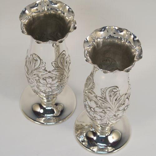 A very pretty Antique Edwardian Sterling Silver pair of table flower vases, having round hand-chased bodies with bellied sides and floral decoration, and all sitting on pedestal feet. These beautiful antique silver vases were made by Charles Edwards of London in 1902. The dimensions of these fine hand-made antique silver pair of vases are height 15 cms (6 inches), diameter at top 6 cms (2.25 inches), and they weigh at total of approx. 278g (9 troy ounces). Please note that these vases are not loaded.

  