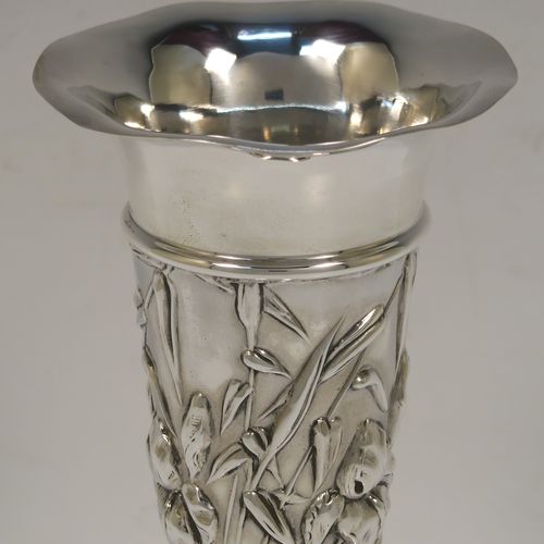 A very pretty Antique Edwardian Sterling Silver pair of table flower vases, having round hand-chased bodies with tapering sides and floral decoration, and all sitting on pedestal feet. These beautiful antique silver vases were made by William Comyns of London in 1903. The dimensions of these fine hand-made antique silver pair of vases are height 16.5 cms (6.5 inches), and diameter at top 7 cms (2.75 inches).   