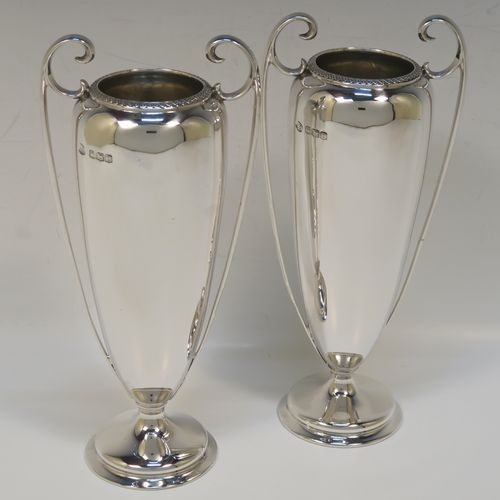 A very handsome pair of Antique Sterling Silver vases, having plain round bodies with tapering sides, with two flying scroll side handles, and  applied double scroll top borders, and all sitting on round pedestal feet. These elegant silver vases were made by John Round of Sheffield in 1920. The dimensions of these fine hand-made antique silver vases are height 19 cms (7.5 inches), spread across arms 9 cms (3.5 inches), diameter of bodies at widest point 6 cms (23 inches), and they weigh approx. 354g (11.4 troy ounces). Please note that these vases are not loaded.   