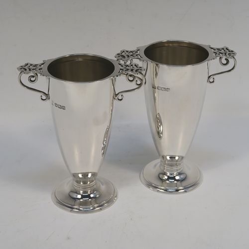 A very elegant pair of Antique Victorian Sterling Silver vases, having plain round bodies with tapering sides, with two scroll side handles and hand-pierced thumb-pieces, and all sitting on round pedestal feet. These handsome silver vases were made by Martin Hall and Co. Ltd., of Sheffield in 1896. The dimensions of these fine hand-made antique silver vases are height 12.5 cms (5 inches), spread across handles 10 cms (4 inches), diameter of bodies at lip 5.5 cms (2.25 inches), and they weigh approx. 277g (8.9 troy ounces). Please note that these vases are not loaded.  