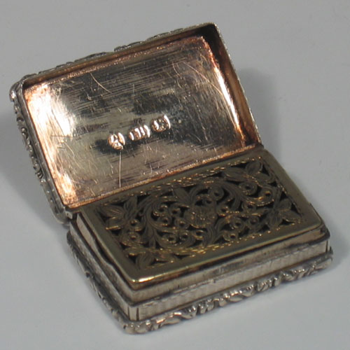 An Antique Georgian Sterling Silver & gold-gilt vinaigrette, having a rectangular body with double cast floral borders top & bottom, with engine-turned decoration, a gold-gilt interior, and a hand-pierced floral grill. Made in Birmingham in 1831. The dimensions of this fine hand-made antique silver vinaigrette are length 3.5 cms (1.3 inches).